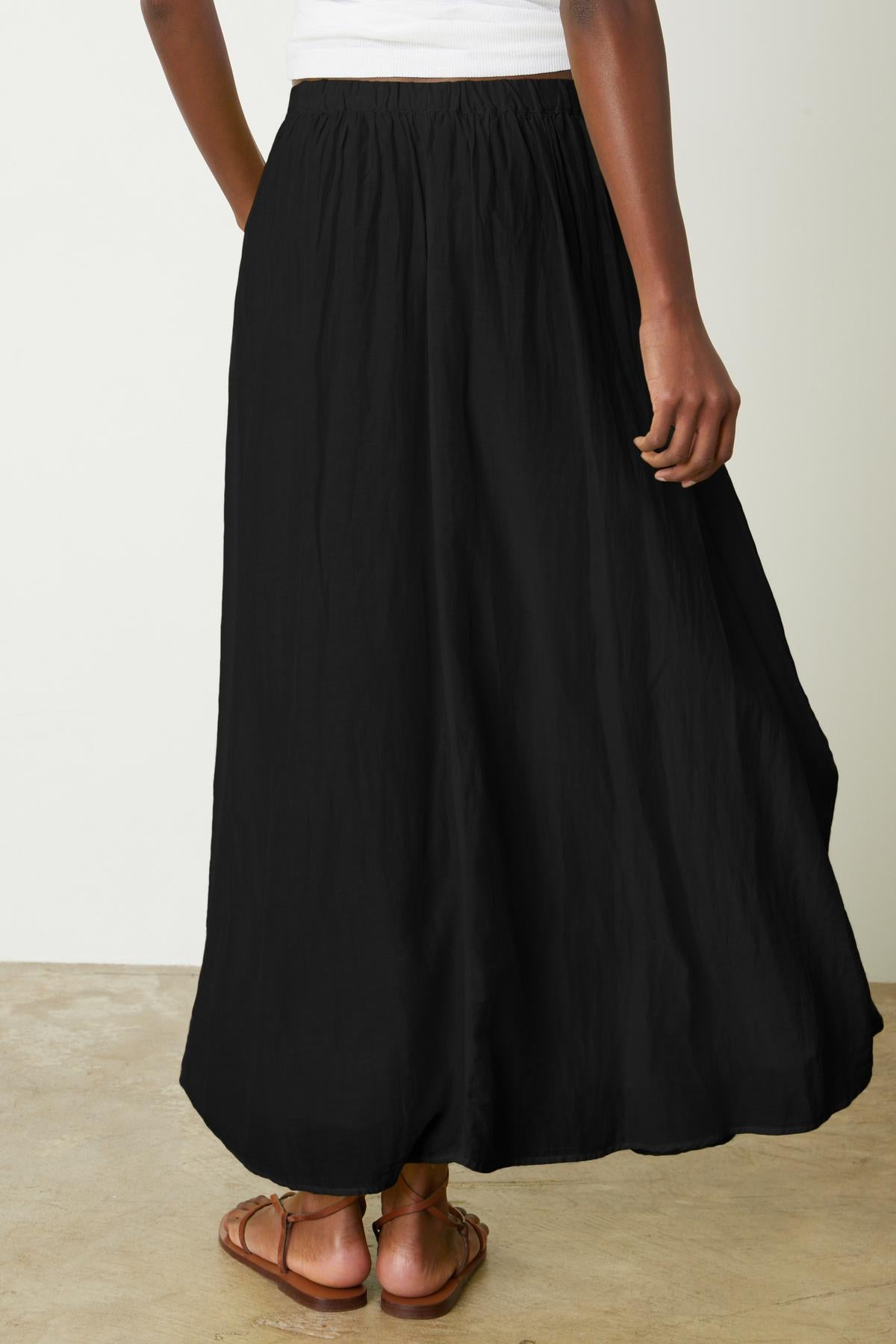 The back view of a woman wearing a Velvet by Graham & Spencer MARIELA MAXI SKIRT.-26262257893569