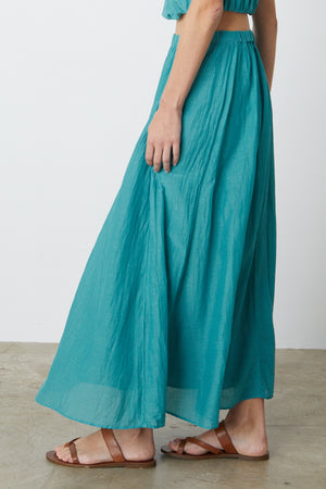 A woman wearing a Mariela Maxi Skirt by Velvet by Graham & Spencer and sandals.