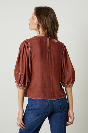the back view of a woman wearing jeans and a Velvet by Graham & Spencer Nancy Silk Velvet Puff Sleeve Top.