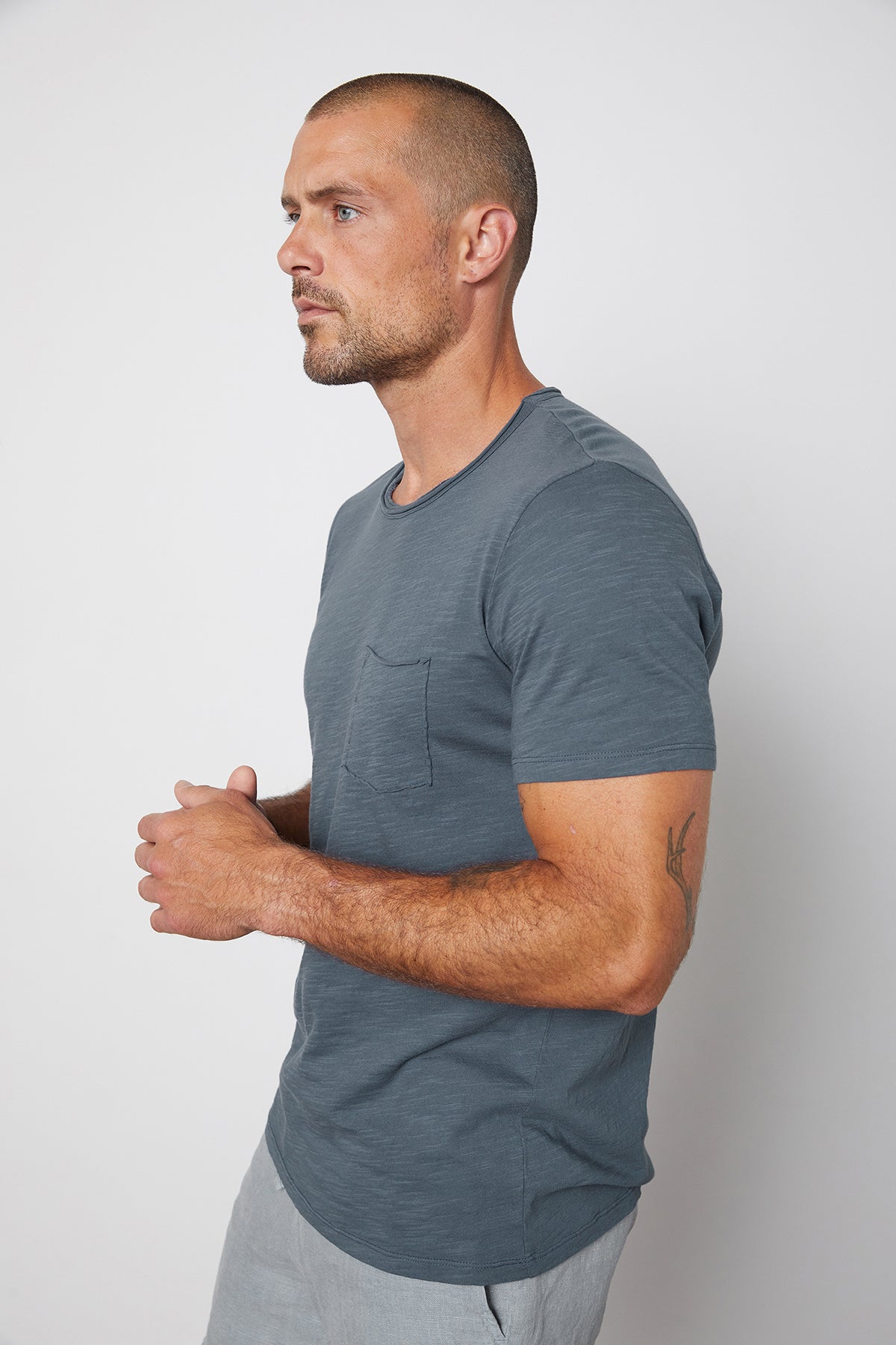 Side view of Chad slub cotton short sleeve tee with raw edges and front pocket in malachite.-25328431661249
