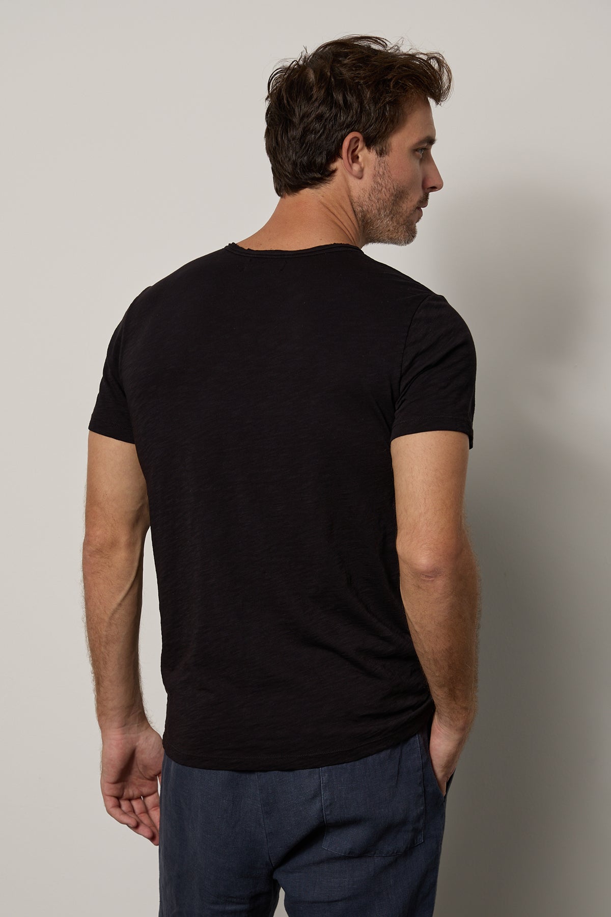   the back of a man wearing a black Velvet by Graham & Spencer CHAD RAW EDGE COTTON SLUB POCKET TEE v-neck t-shirt. 
