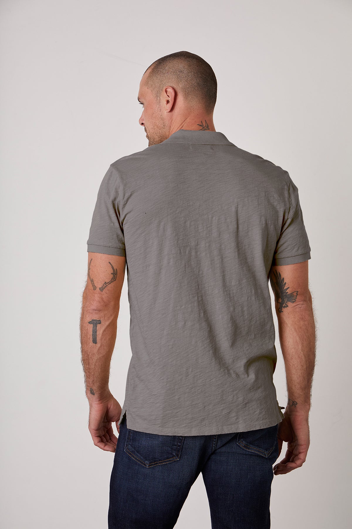   The NIKO POLO by Velvet by Graham & Spencer showcases the timeless style of a man wearing jeans and a grey polo shirt. 