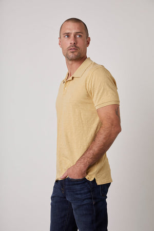 A man wearing the Velvet by Graham & Spencer NIKO POLO silhouette in a yellow cotton slub.
