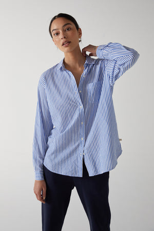 Model Standing with One Arm Up Wearing Newport Blue and White Stripe Button Down Cotton Shirt Front
