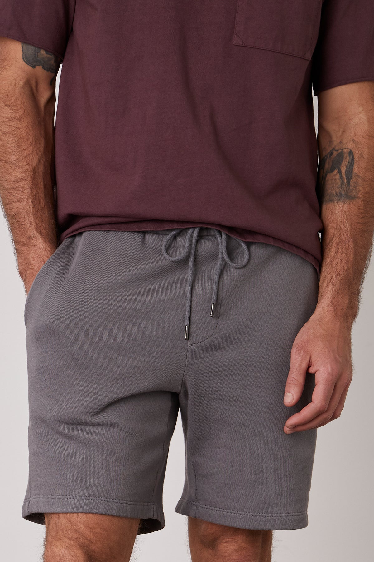  A man wearing grey JAXSON DRAWSTRING SHORTs and a maroon t-shirt in a casual short, with extra soft fleece interior by Velvet by Graham & Spencer. 
