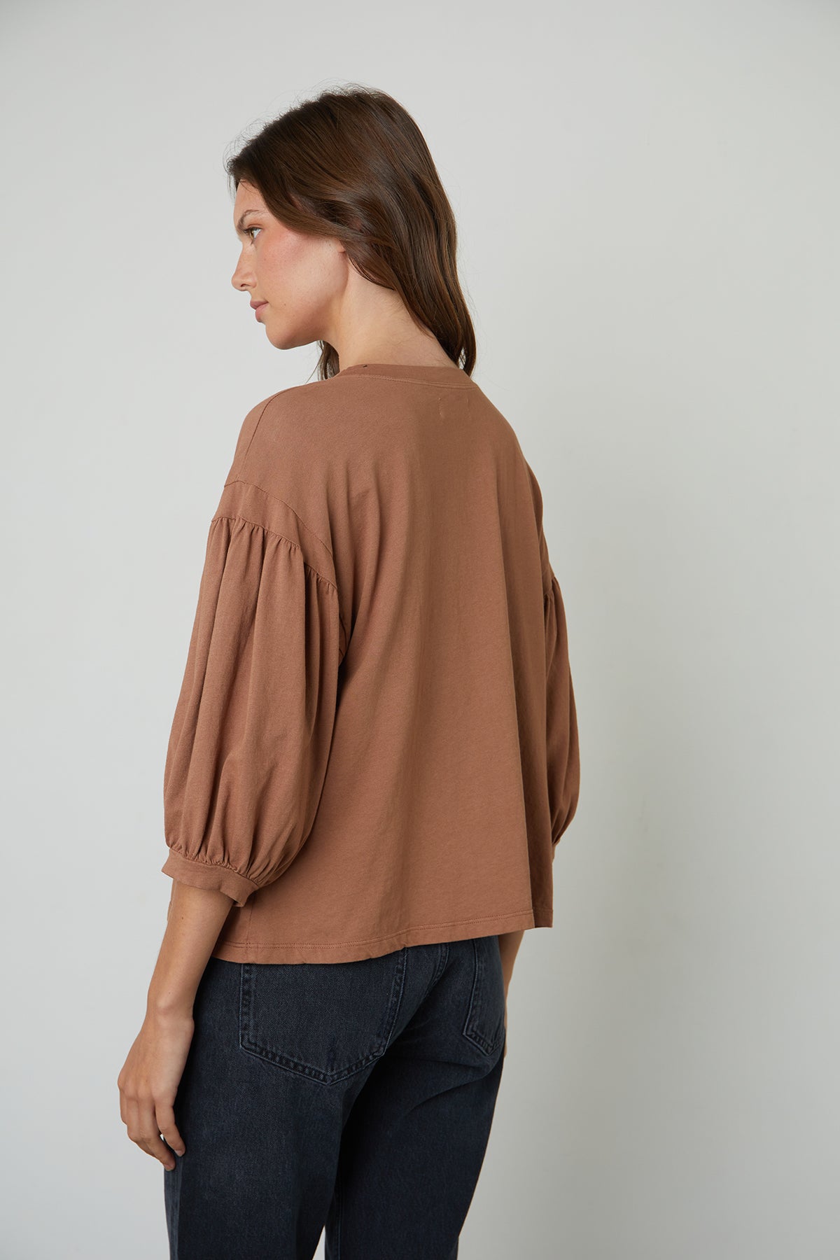   The back view of a woman wearing a Velvet by Graham & Spencer PRUDY 3/4 SLEEVE TEE that adds volume to her overall aesthetic. 