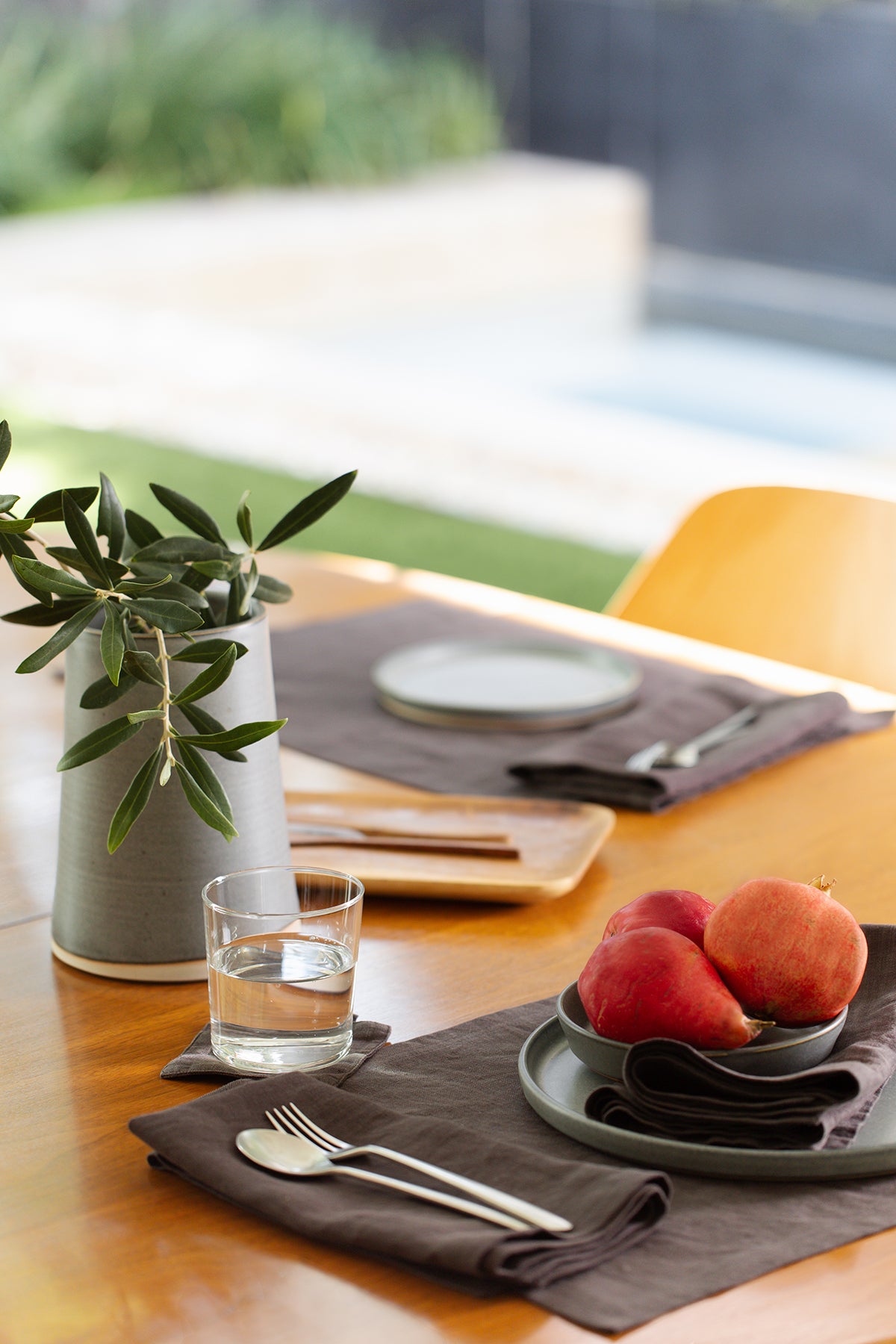   A Jenny Graham Home linen placemat on a table accessorizes the scene next to a bowl of peaches. 