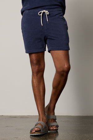 A man wearing a pair of Velvet by Graham & Spencer OZZIE TERRY SHORT and sandals.