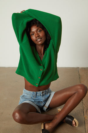 a black woman wearing a Velvet by Graham & Spencer YASMINE BUTTON FRONT CARDIGAN and denim shorts.