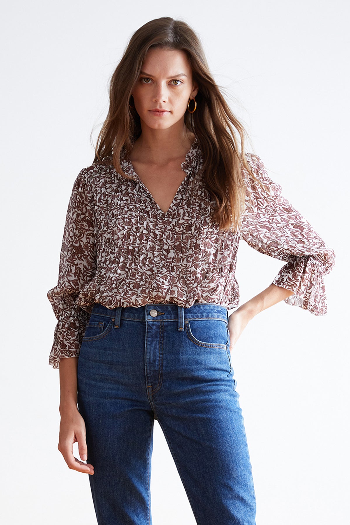 A woman with long hair wearing a Velvet by Graham & Spencer's WILONA PRINTED RUFFLE BLOUSE and blue jeans, standing against a plain white background.-7755171496017