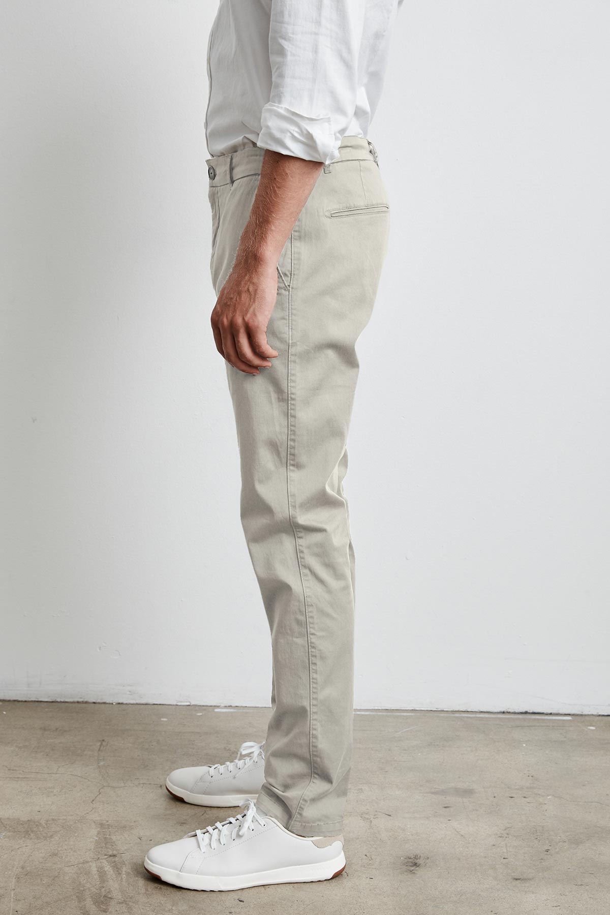   A man wearing a white shirt and Velvet by Graham & Spencer BROGAN COTTON TWILL PANT standing in front of a white wall during work. 
