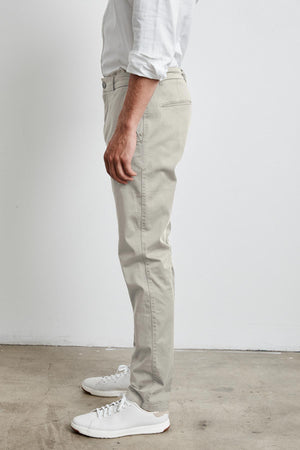 A man wearing a white shirt and Velvet by Graham & Spencer BROGAN COTTON TWILL PANT standing in front of a white wall during work.