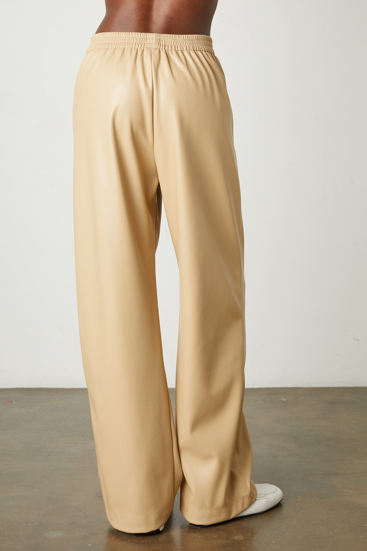   The back view of a woman wearing Velvet by Graham & Spencer's JENNA VEGAN LEATHER WIDE LEG PANT in eco-chic holiday style. 