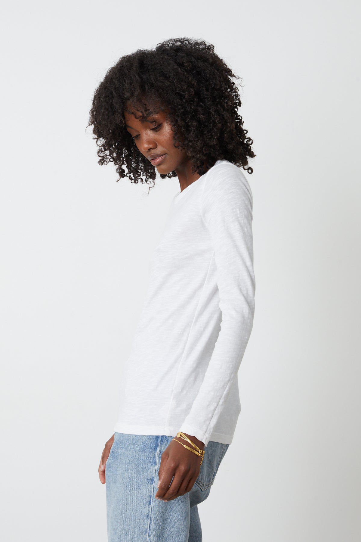   The model is wearing a white Lizzie Original Slub Long Sleeve Tee by Velvet by Graham & Spencer and jeans. 