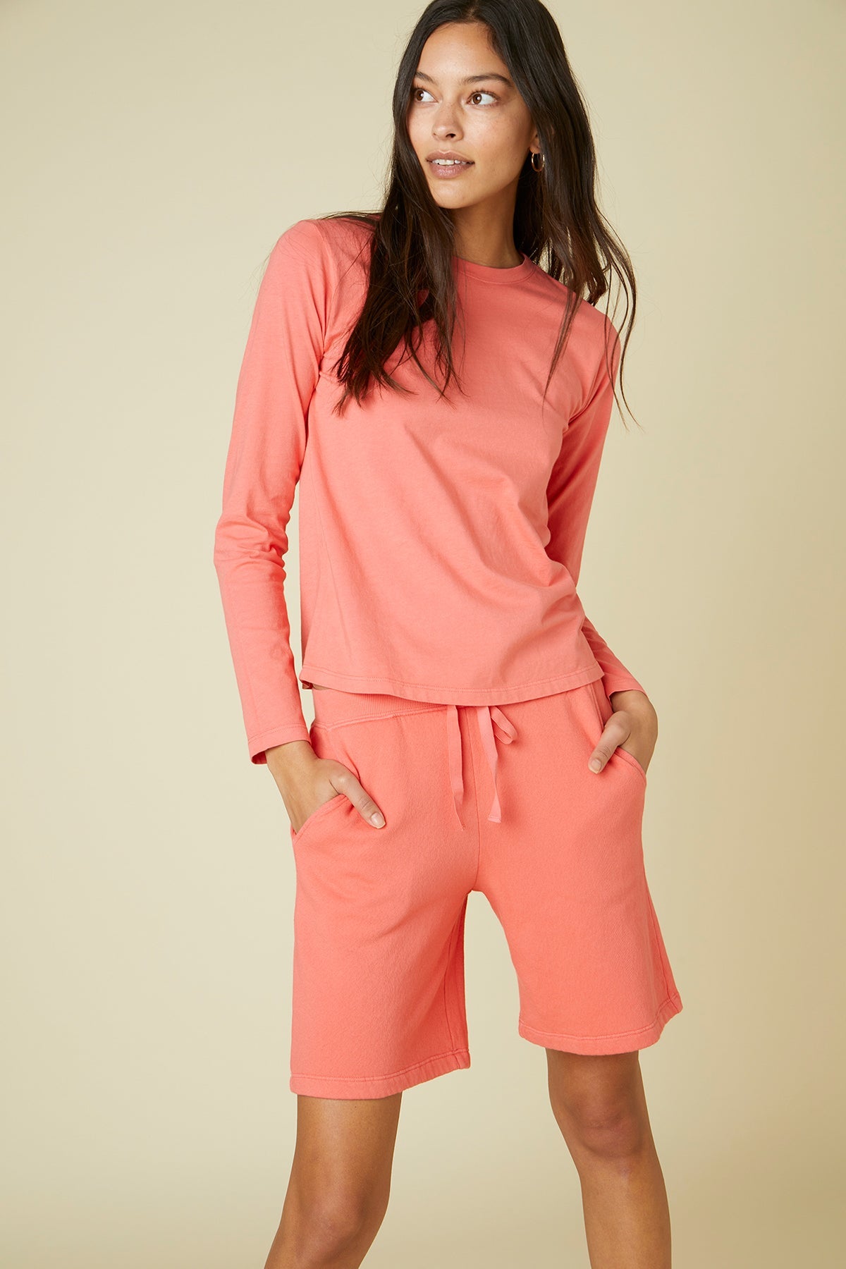   The model is wearing a coral long-sleeved top and Velvet by Jenny Graham Laguna Sweatshorts. 