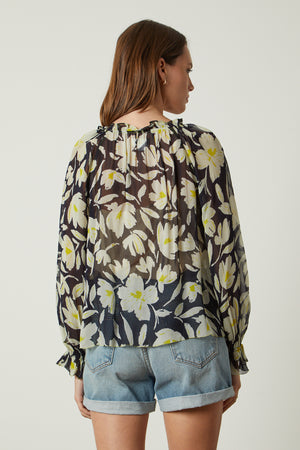 The back view of a woman wearing the Velvet by Graham & Spencer MILEY PRINTED TOP with floral print.