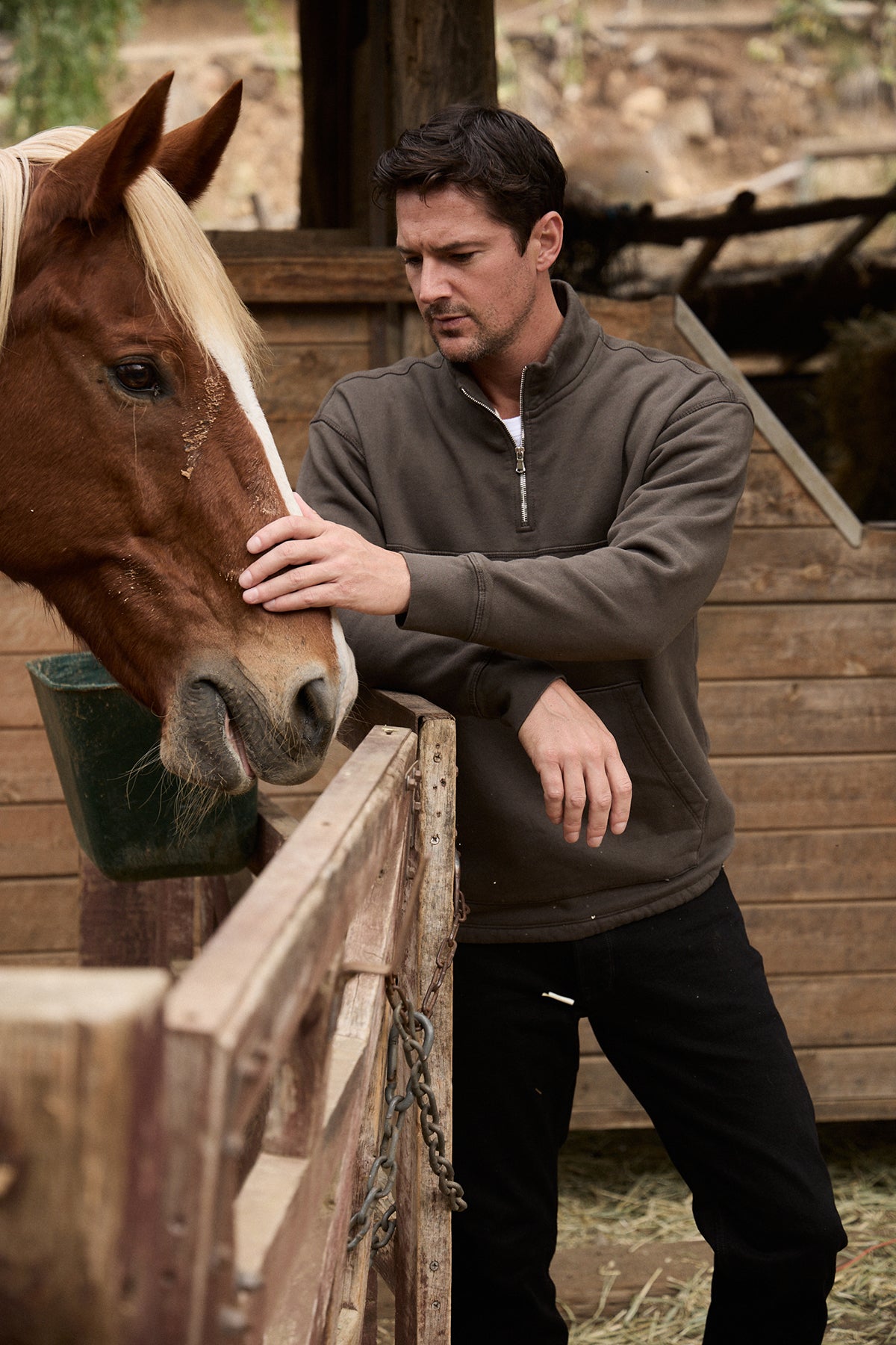 Model standing outdoors petting horse wearing Baldwin Quarter-Zip Sweatshirt in dillweed front-25601315635393