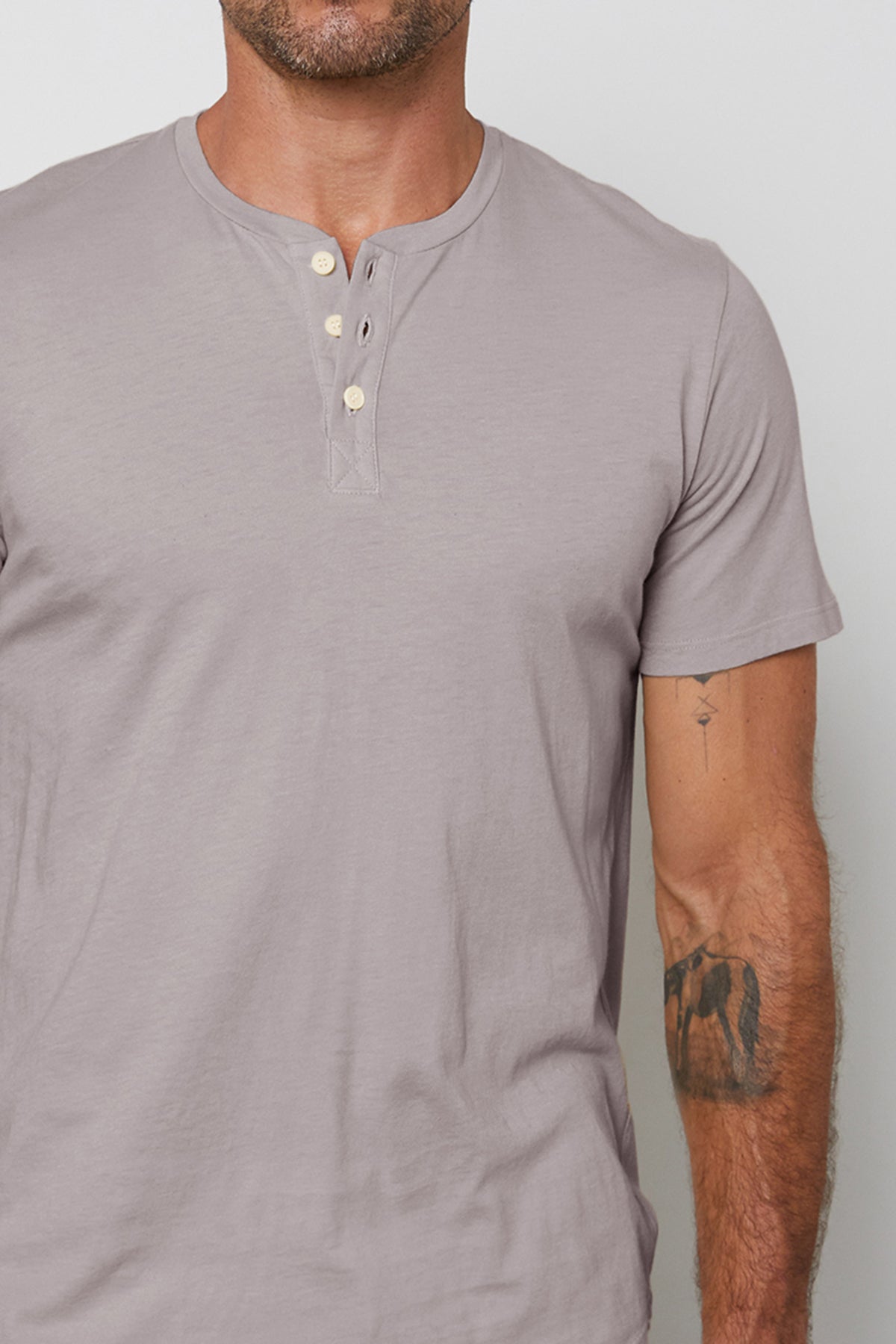 A man wearing a classic grey Velvet by Graham & Spencer Fulton Short Sleeve Henley made of cotton jersey.-26011328184513