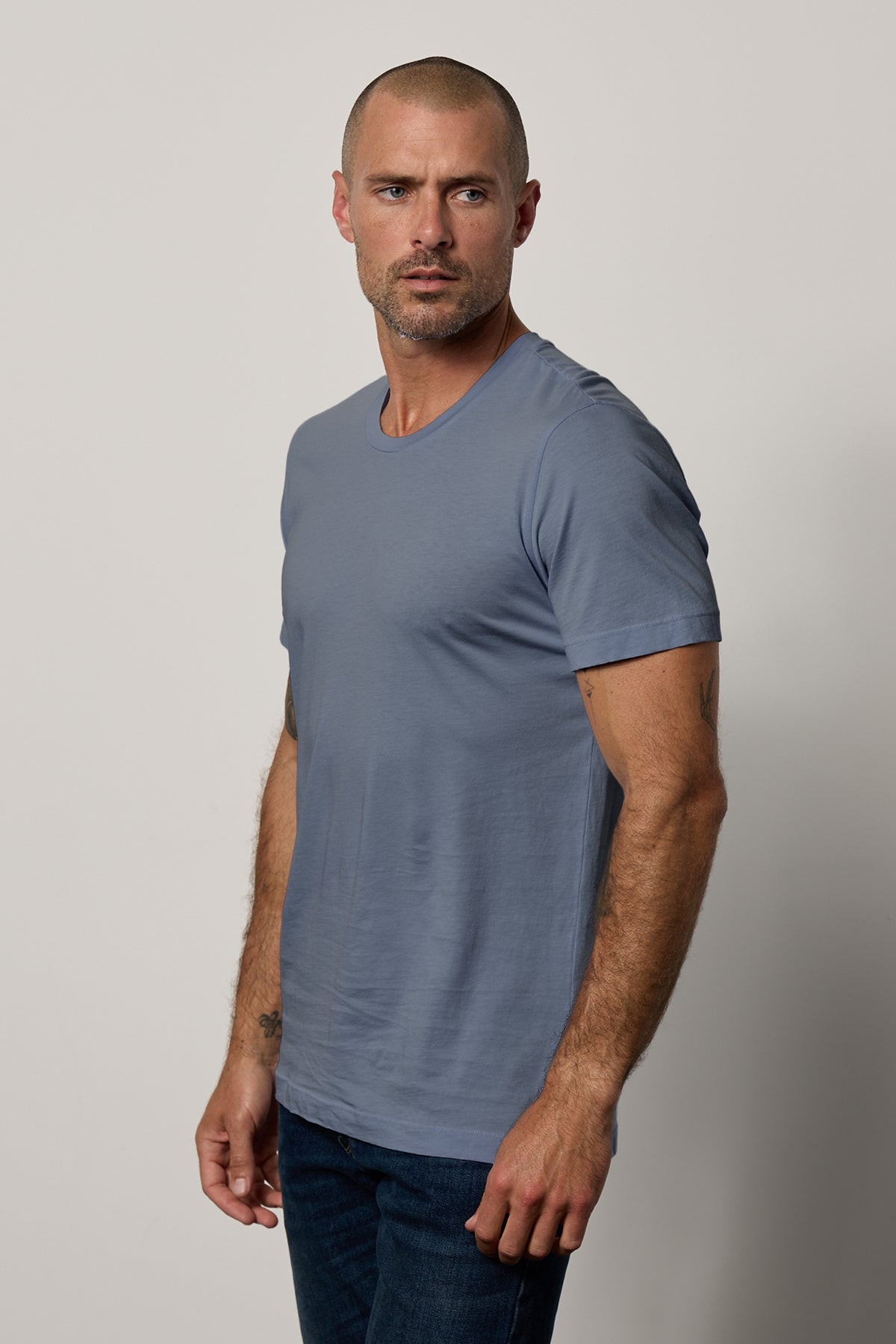 The man, dressed in a Velvet by Graham & Spencer HOWARD WHISPER CLASSIC CREW NECK TEE and jeans, exuded effortless style and comfort with his lightweight cotton knit attire.-25793661239489