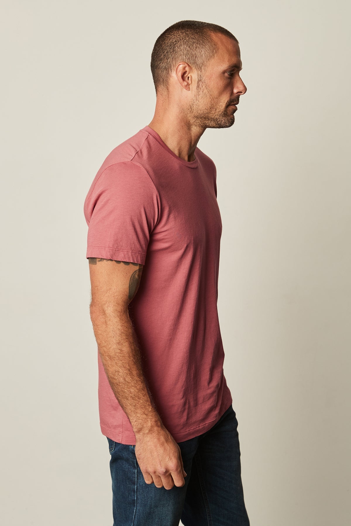   A man wearing a Vintage-Feel Pink Velvet by Graham & Spencer Howard Whisper Classic Crew Neck Tee and jeans, crafted from lightweight cotton knit fabric. 