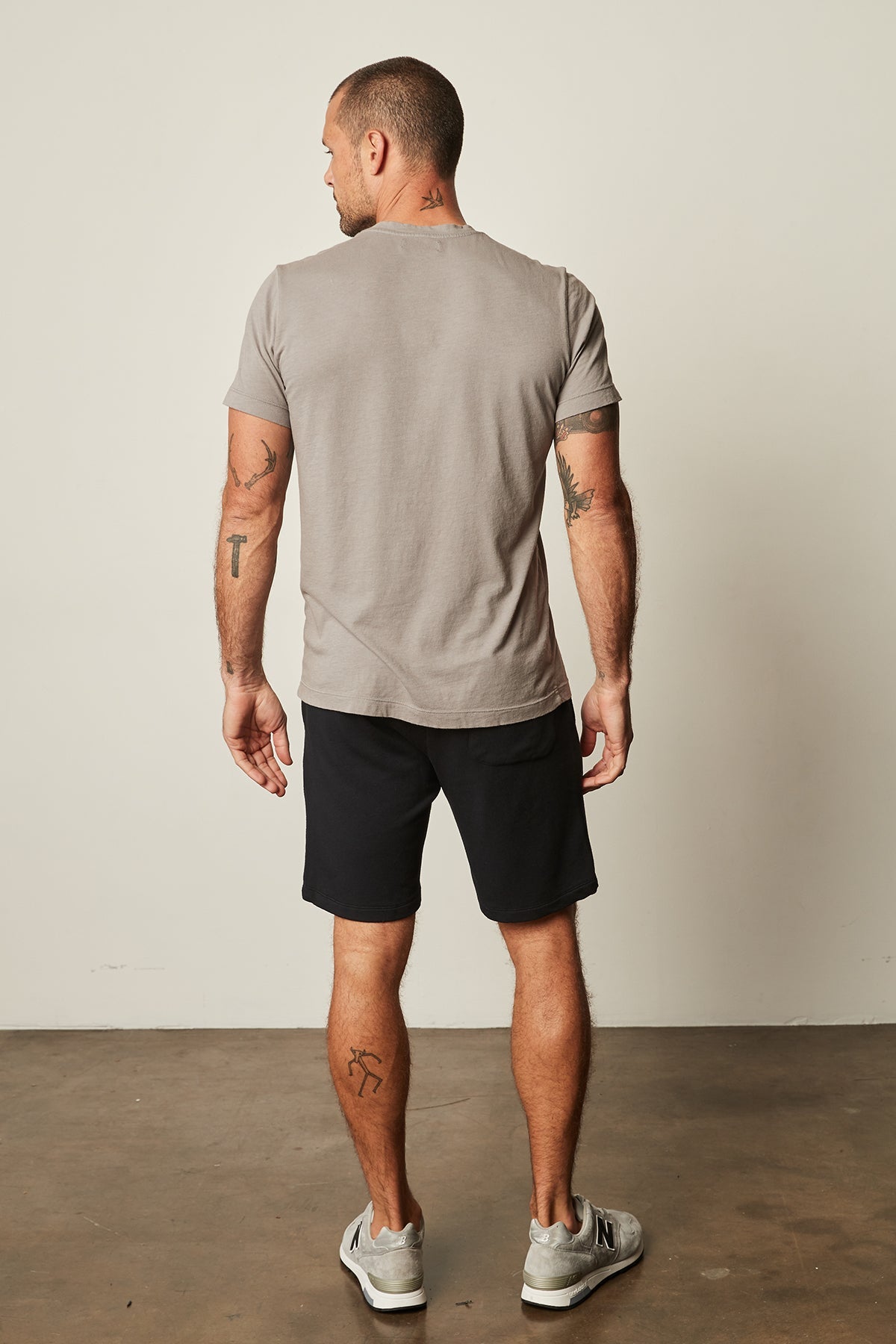   The back view of a man wearing a Velvet by Graham & Spencer lightweight cotton knit grey HOWARD WHISPER CLASSIC CREW NECK TEE and black shorts. 