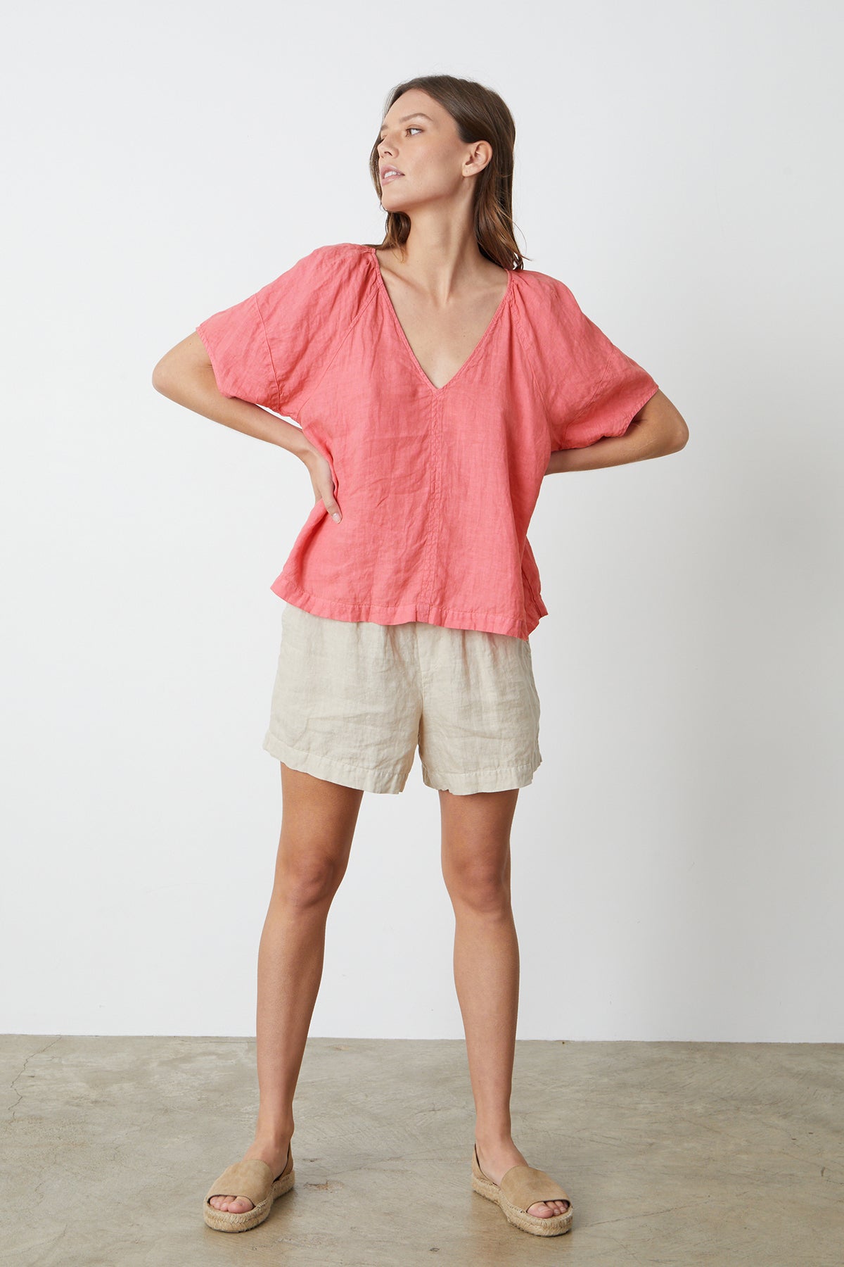 A woman standing in front of a white wall wearing the CALLIN PUFF SLEEVE LINEN TOP in rosebay by Velvet by Graham & Spencer with Tammy shorts and sandals, full length front-26262345580737