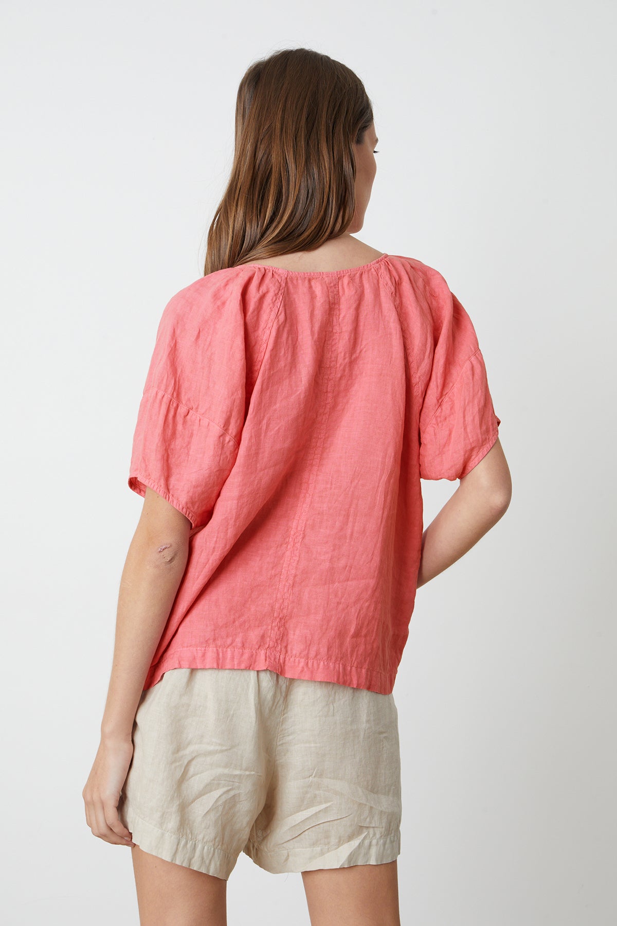 the back view of a woman wearing a Velvet by Graham & Spencer CALLIN PUFF SLEEVE LINEN TOP and tan shorts.-26262345646273