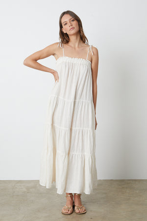 A model wearing a white Velvet by Graham & Spencer CHARLIE LINEN TIERED DRESS and sandals.