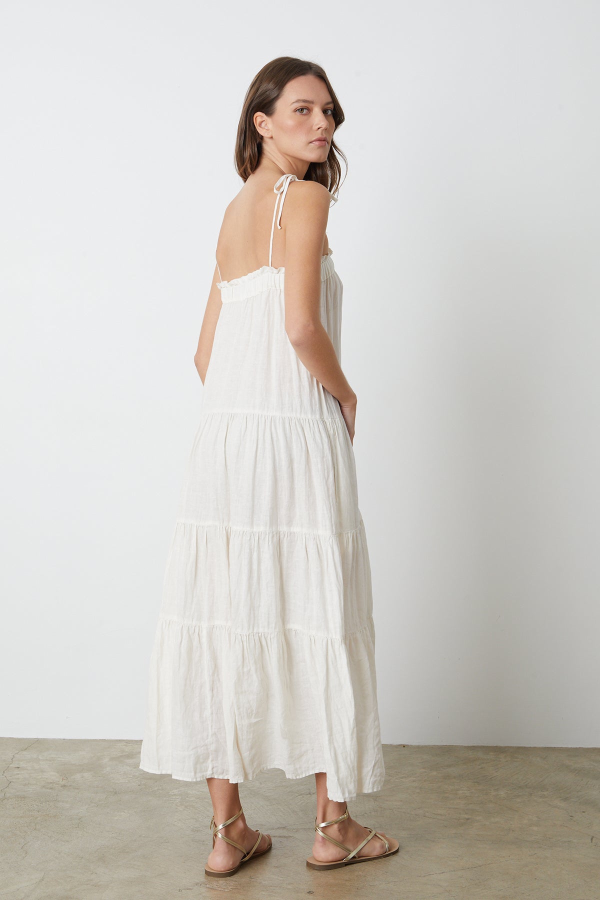 The back view of a woman wearing a Velvet by Graham & Spencer CHARLIE LINEN TIERED DRESS.-26296070602945