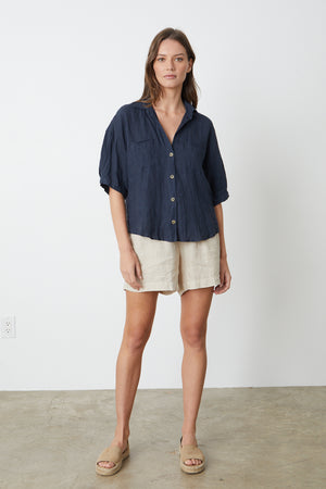 The model is wearing a MARIA LINEN BUTTON-UP SHIRT by Velvet by Graham & Spencer and tan shorts.