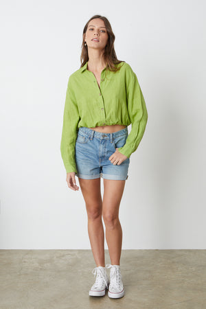 The model is wearing a Velvet by Graham & Spencer CROPPED SHIRT and denim shorts.