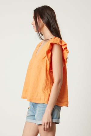 Ava Linen V-Neck Top in orange heat color with blue denim shorts side