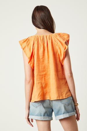 Ava Linen V-Neck Top in orange heat color with blue denim shorts back