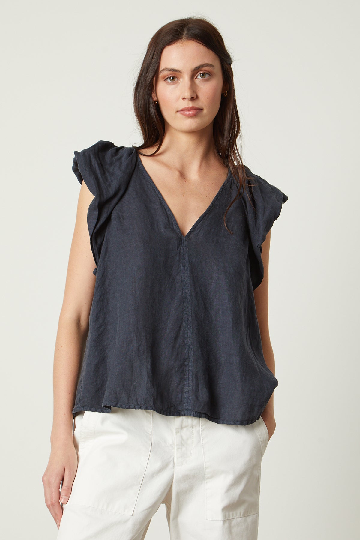   Women with hand in pocket wearing Ava Linen V-Neck Top shadow blue with Mya pant in sleet white front 