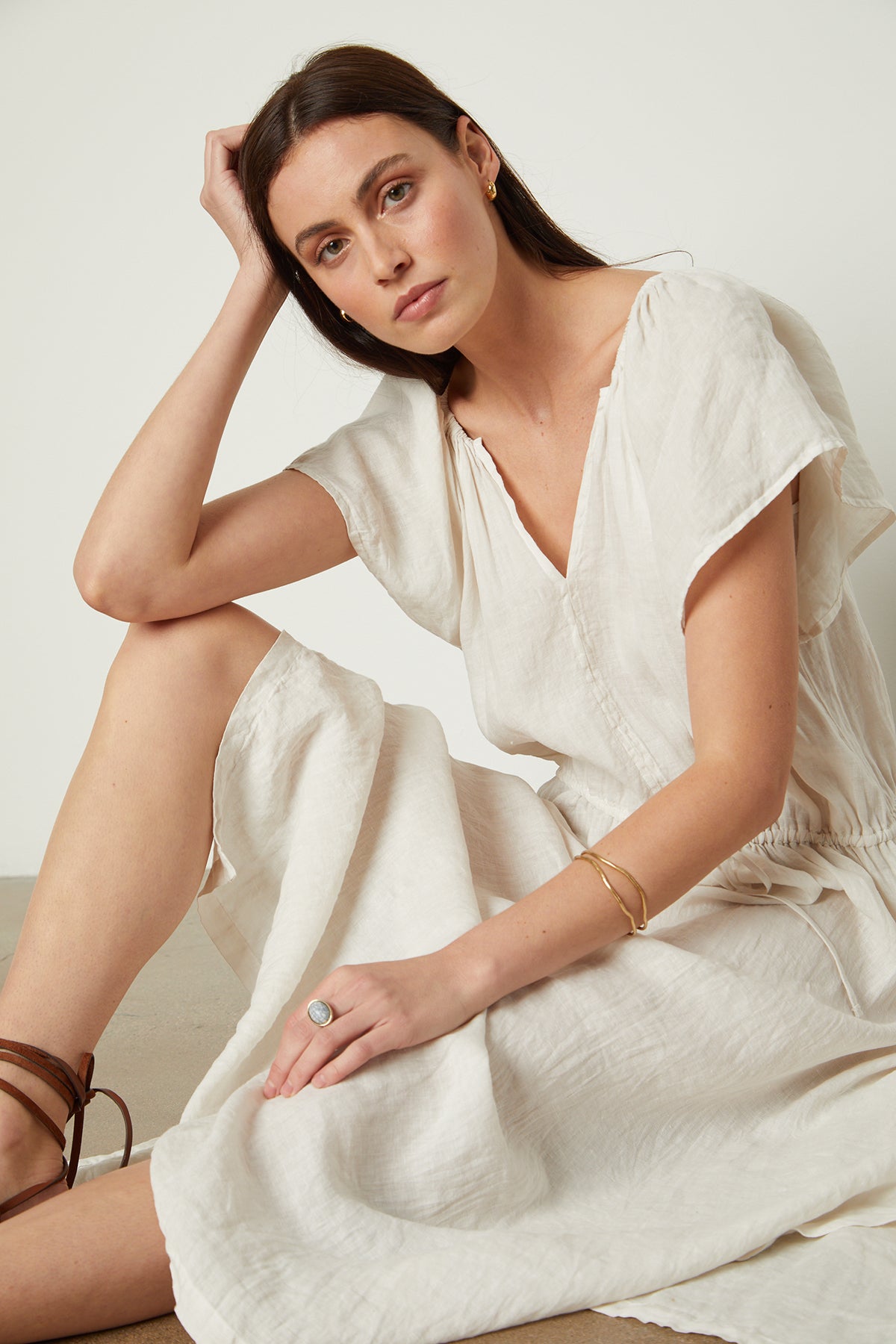 Model sitting on floor leaning on arm wearing Debbie Linen Dress in cream with jewelry front-26143134548161