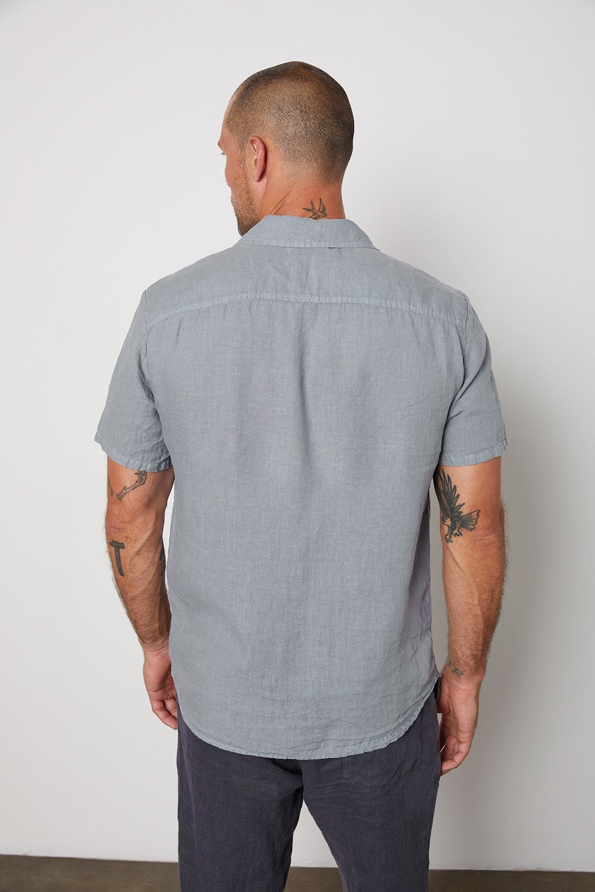 The back of a man wearing a Velvet by Graham & Spencer MACKIE LINEN BUTTON-UP SHIRT with tattoos.-25578273538241