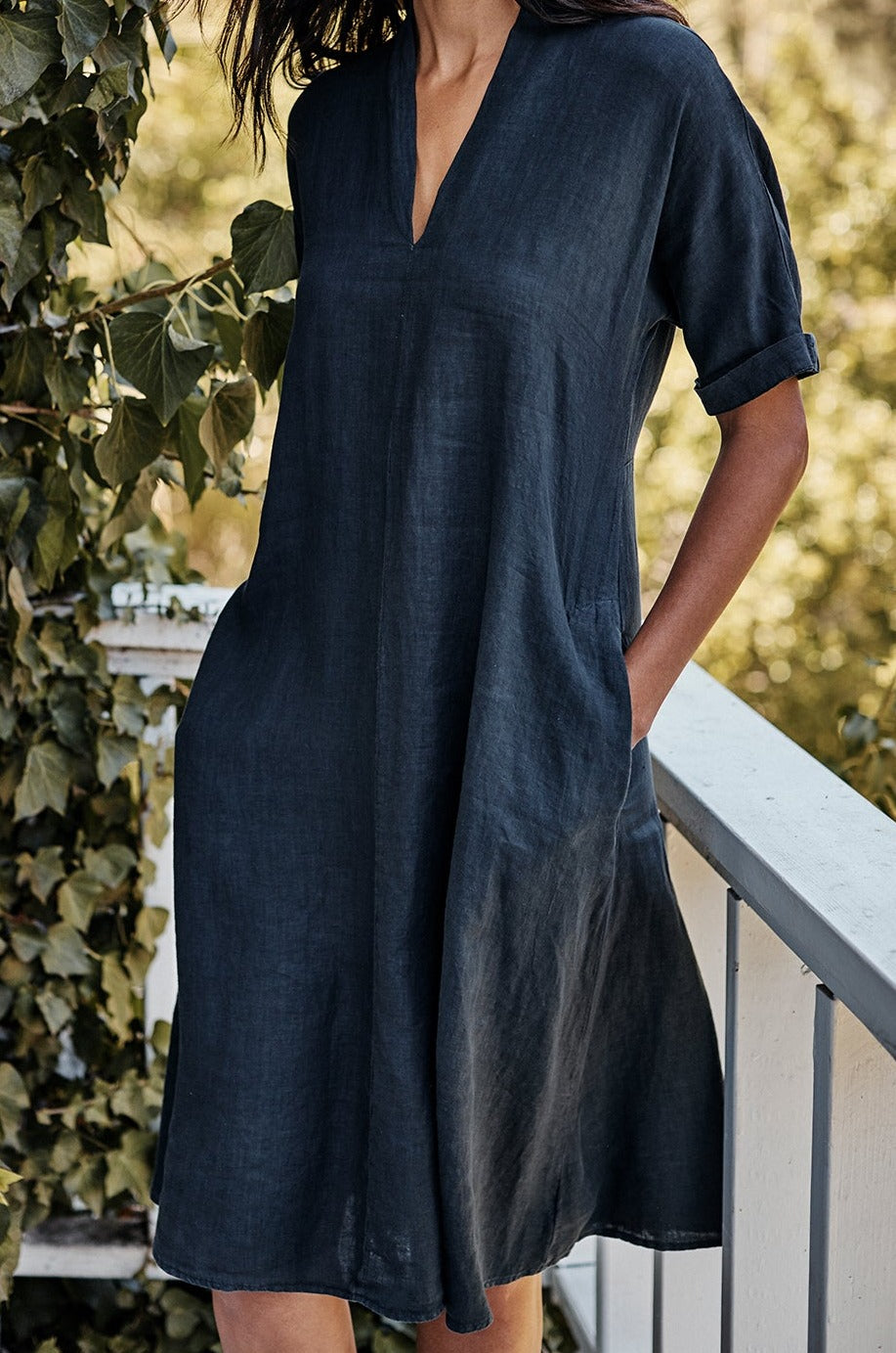   A woman is standing on a balcony wearing a WINLEY LINEN DRESS by Velvet by Graham & Spencer. 
