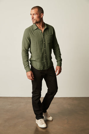 A man wearing the Velvet by Graham & Spencer ELTON button-up shirt with black pants.