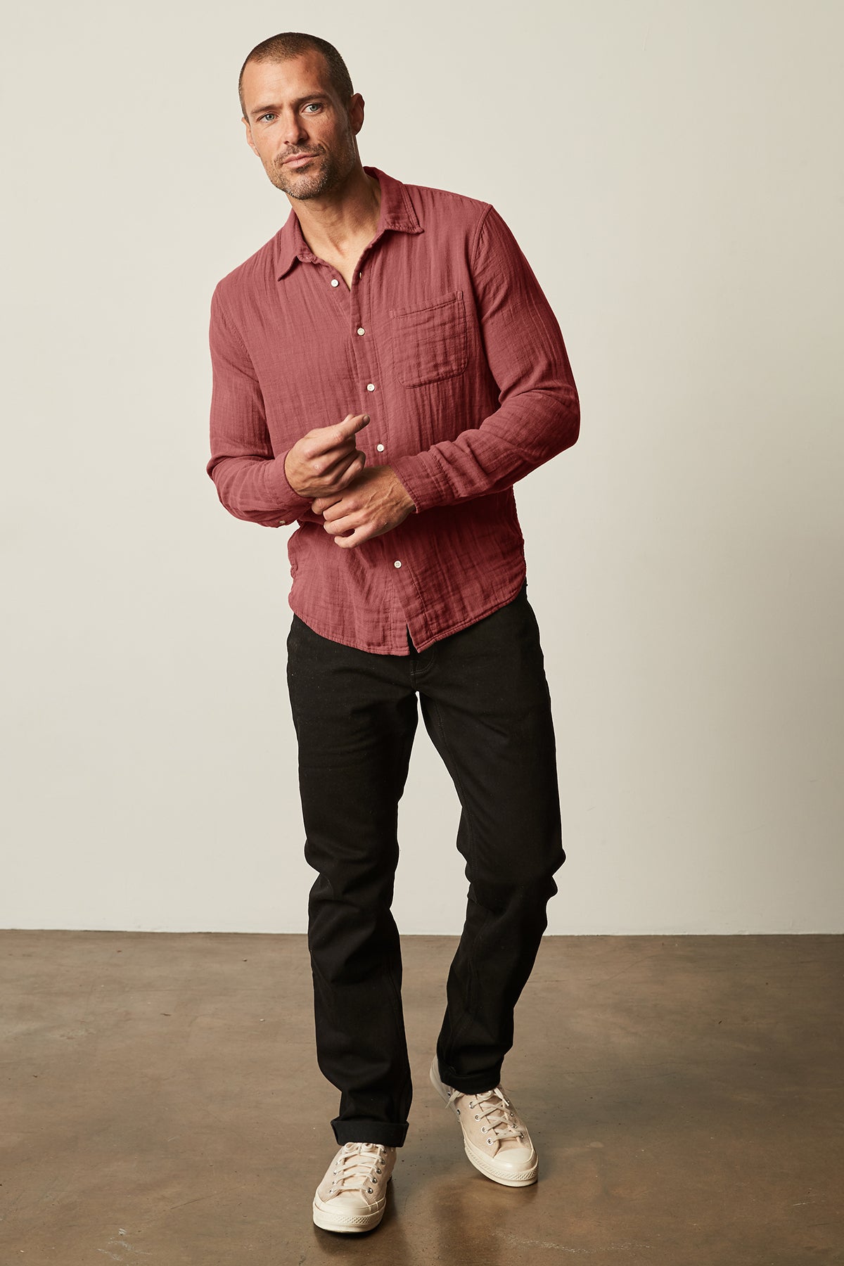 A man wearing a Velvet by Graham & Spencer ELTON BUTTON-UP SHIRT made of natural texture cotton gauze woven fabric and black pants.-25793275658433