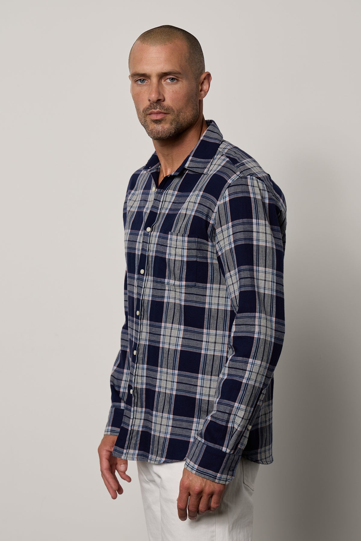   a man wearing a LEONARD PLAID BUTTON-UP SHIRT by Velvet by Graham & Spencer and white pants. 